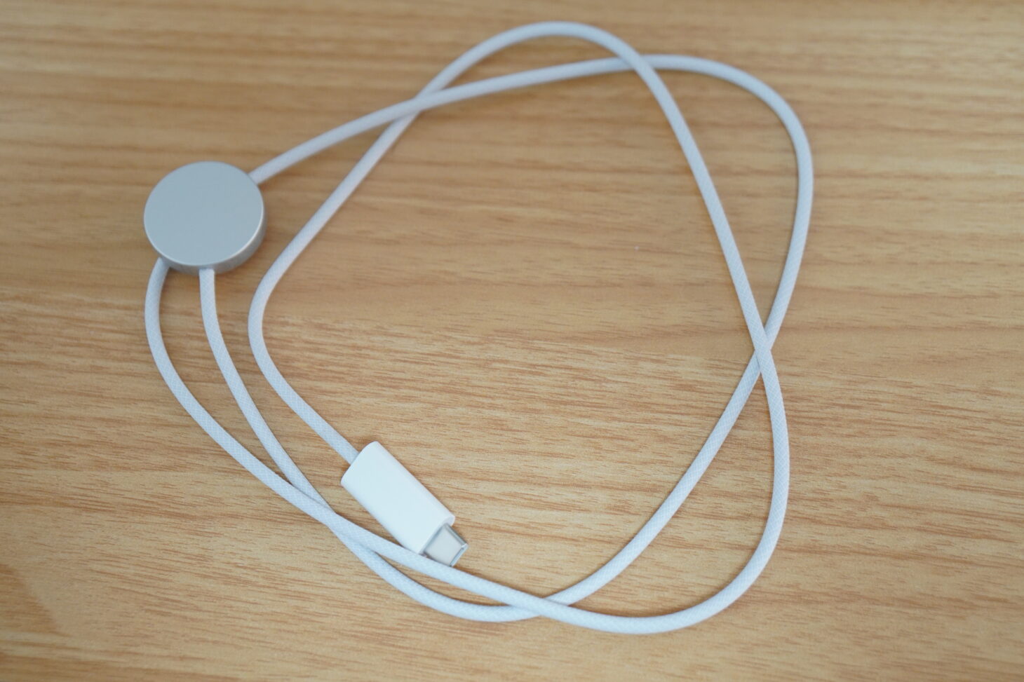 机に置かれた白いApple Watch磁気充電ケーブルのアップ