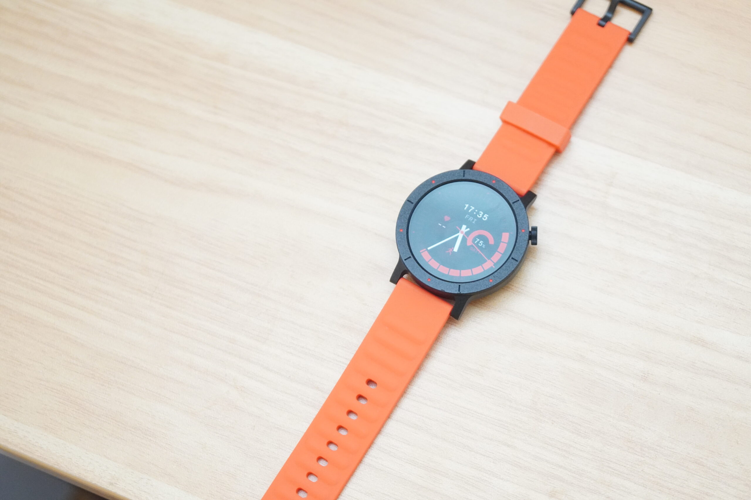 テーブルに置かれたCMF Watch 3 Pro。オレンジのバンドと円形の文字盤
