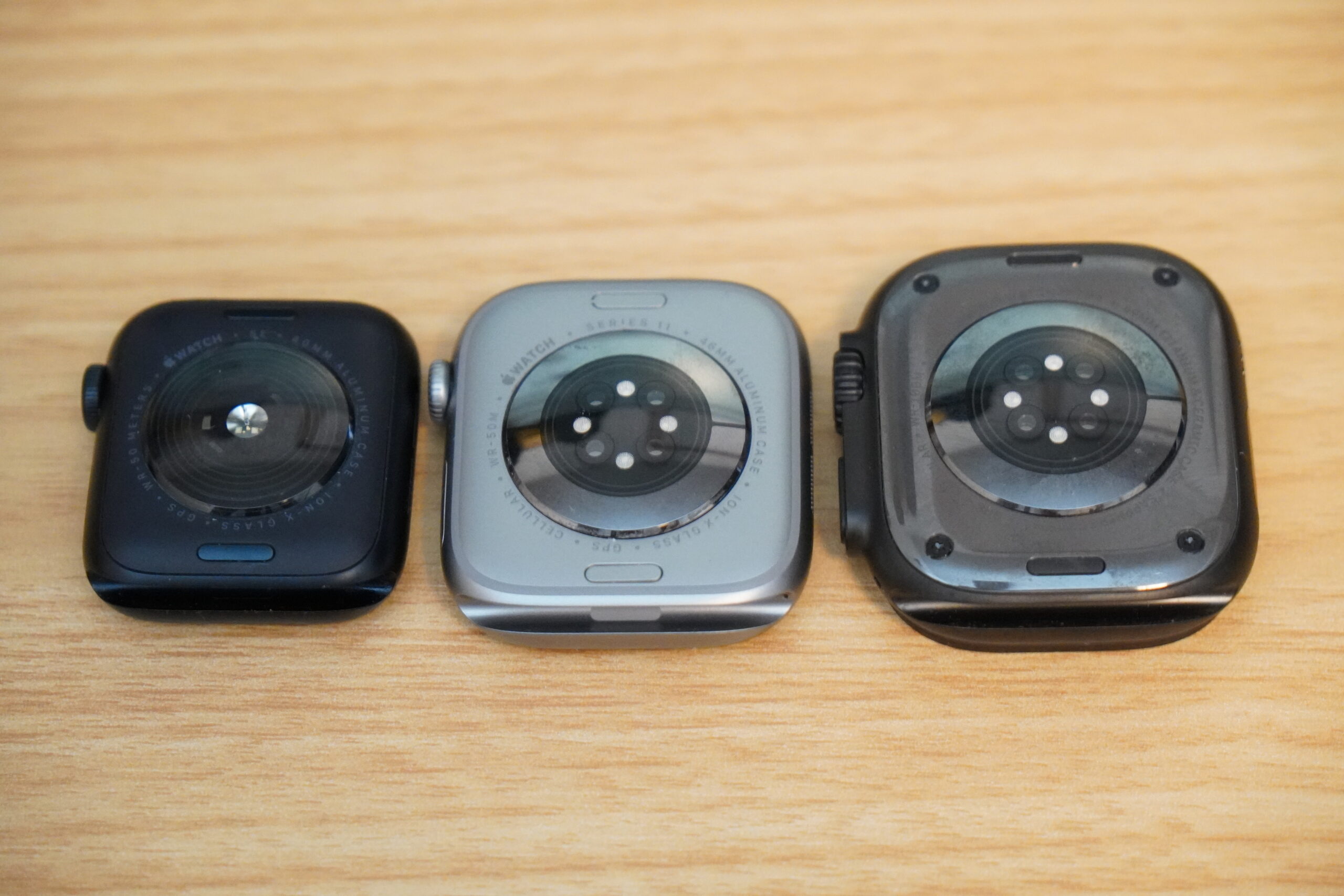 Apple Watch SE 3・Series 11・Ultra 3の裏蓋を並べた写真。中央の光学式センサーと電極が見える