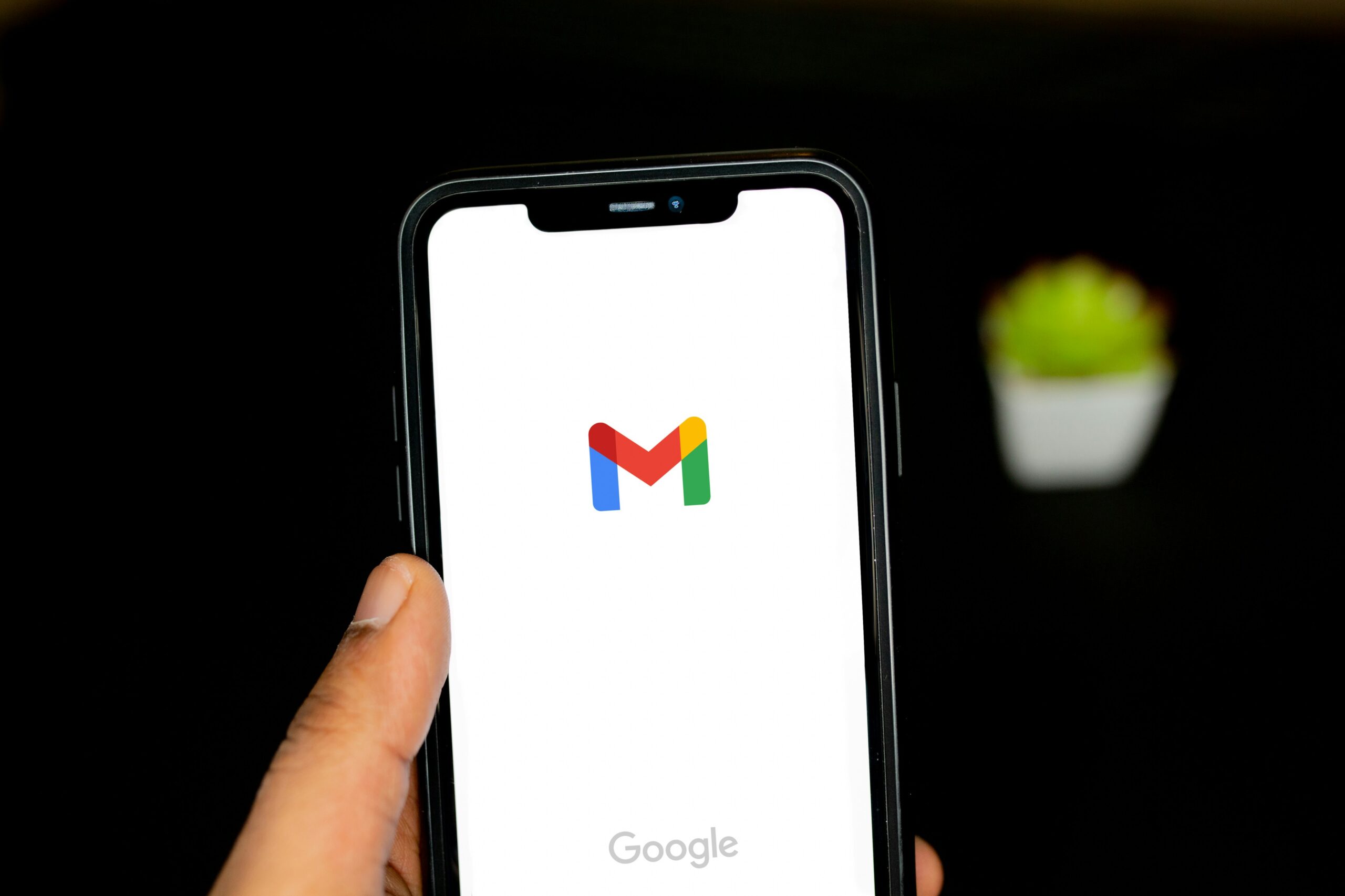 暗い背景の中でGmailの起動画面を表示したスマートフォン