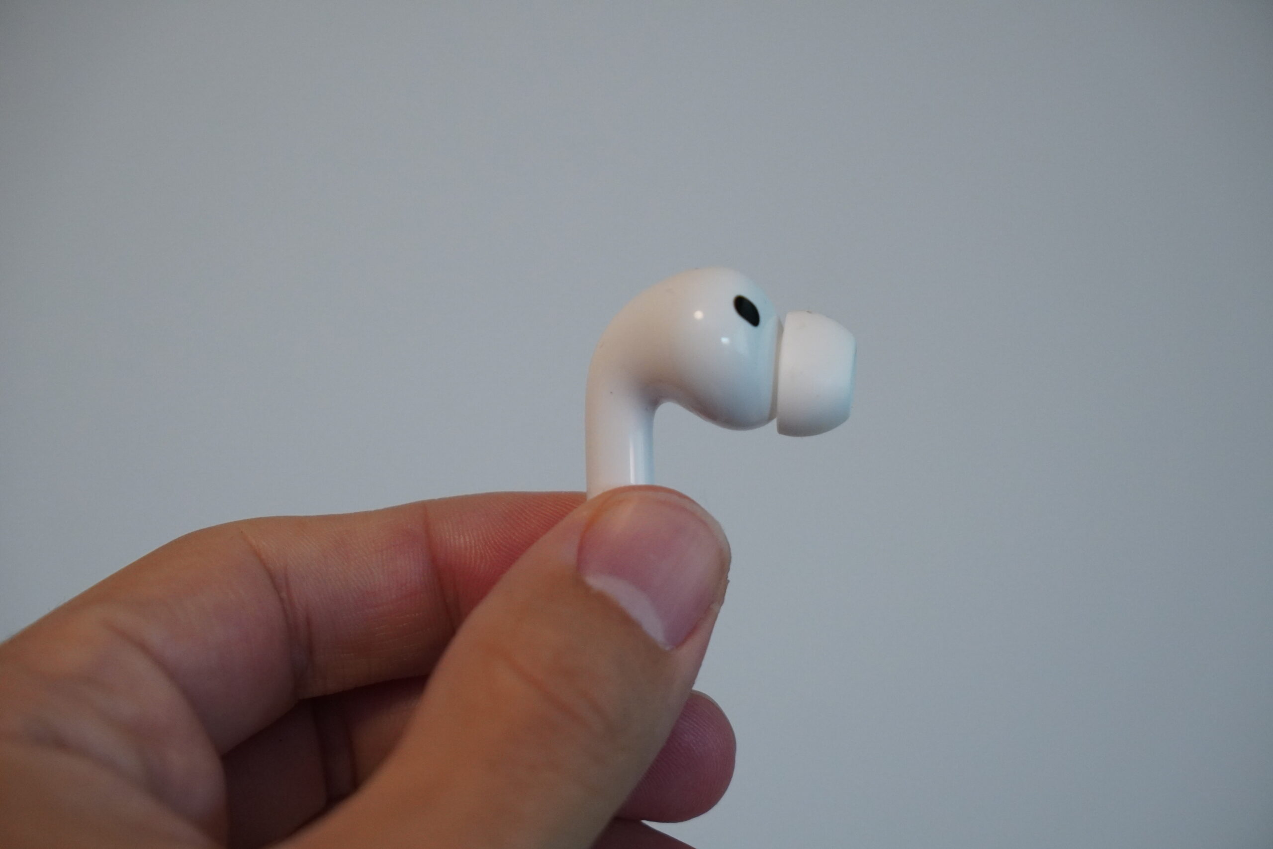 AirPods Pro 3の本体を指でつまんでイヤーチップの形状を見せているところ