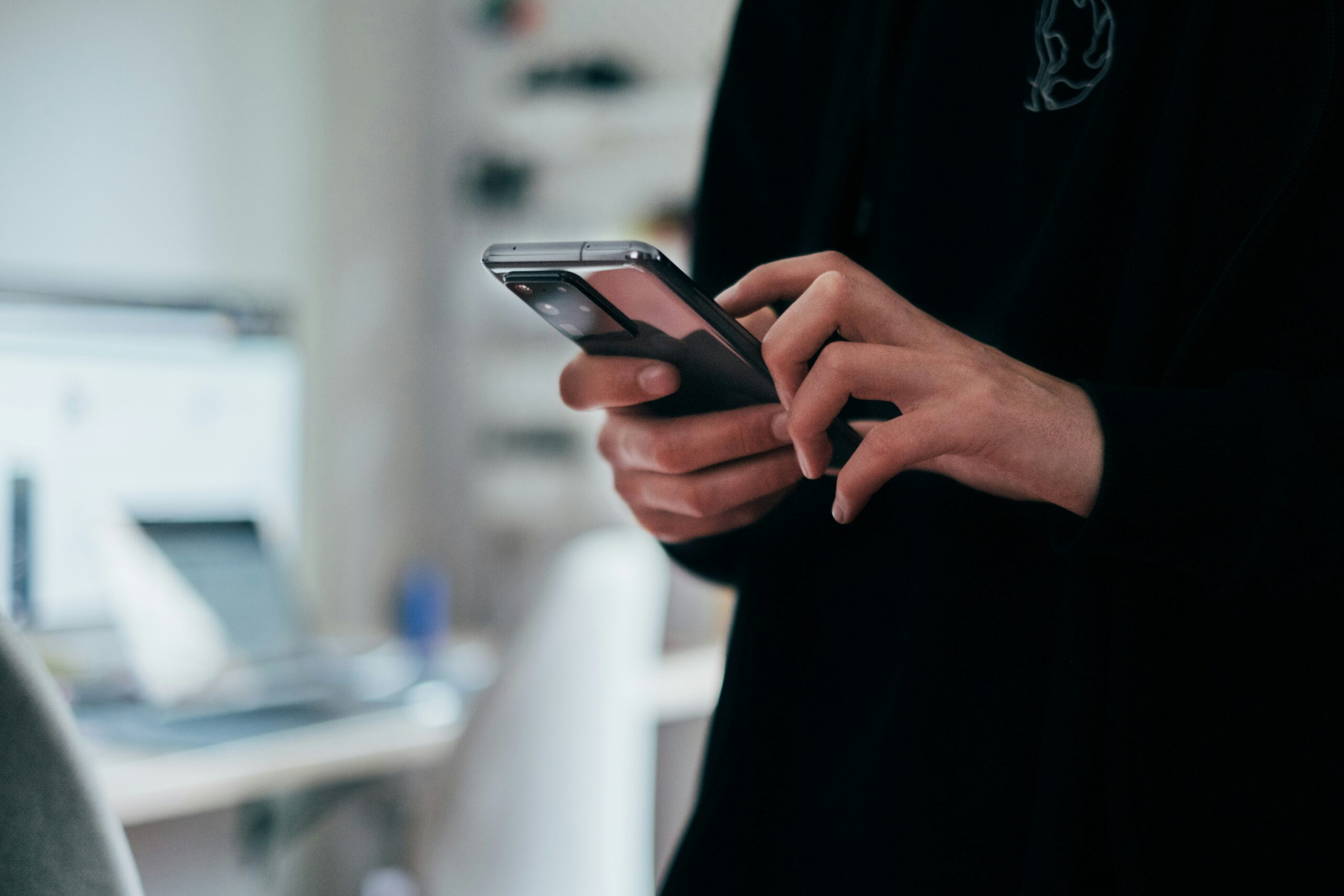 スマートフォンを両手で持ってメッセージを操作している人の手元