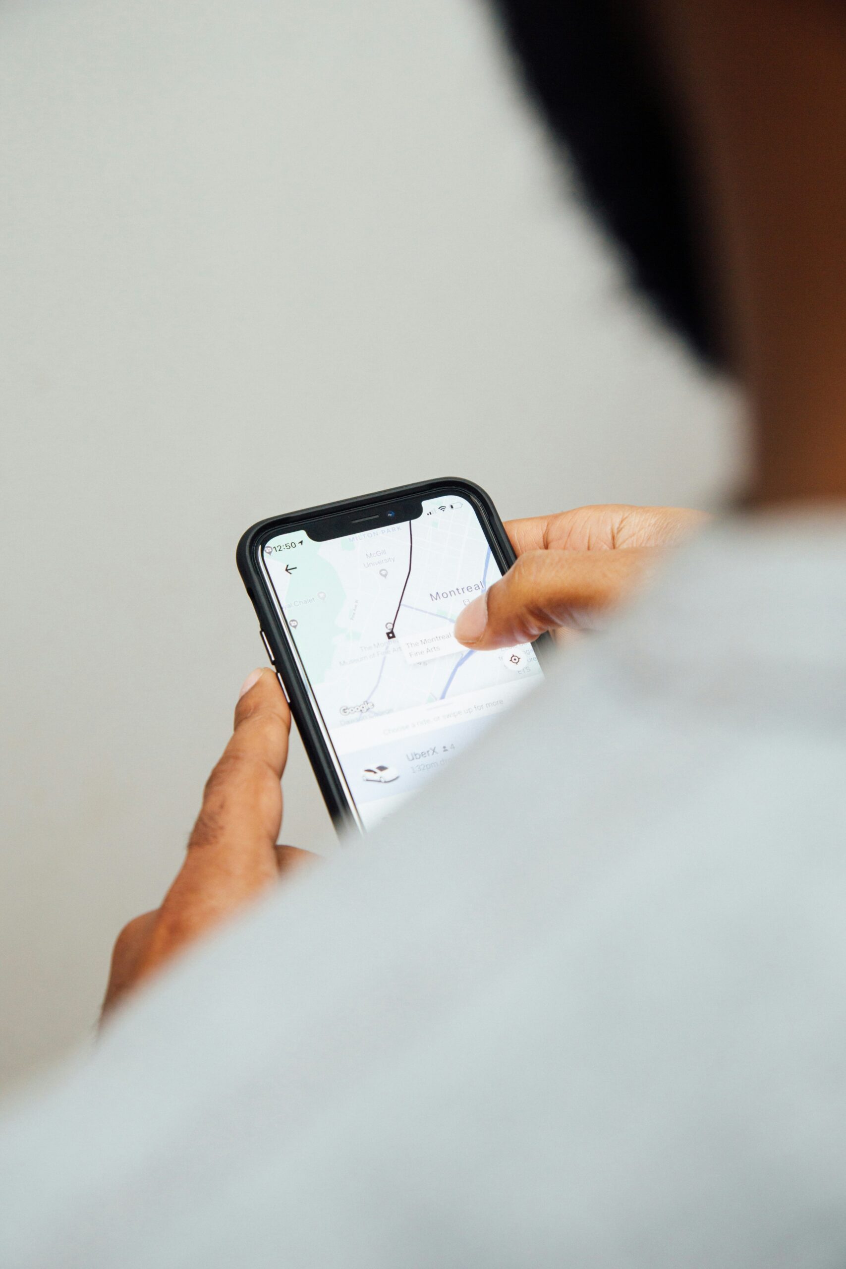 白い服の人物がノッチ付きiPhoneで地図アプリを操作している手元