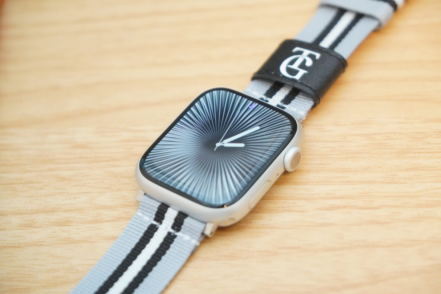 白黒ストライプのナイロンバンドを着けたApple Watchを木製テーブルに置いた様子