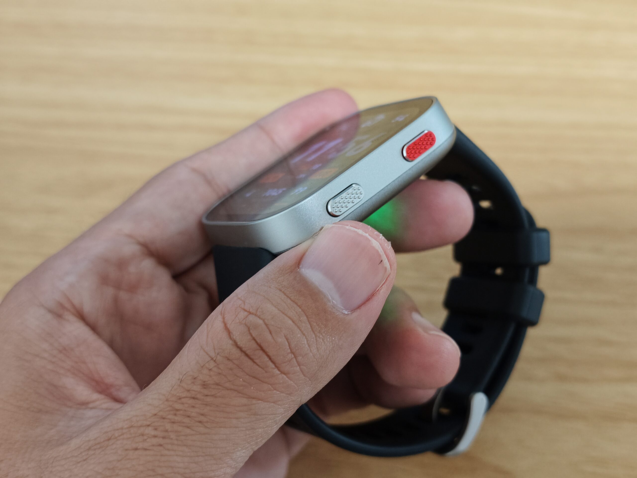 Amazfit Bip Maxの横からの厚みショット。物理ボタン2つと背面の緑LEDセンサーの光が見える