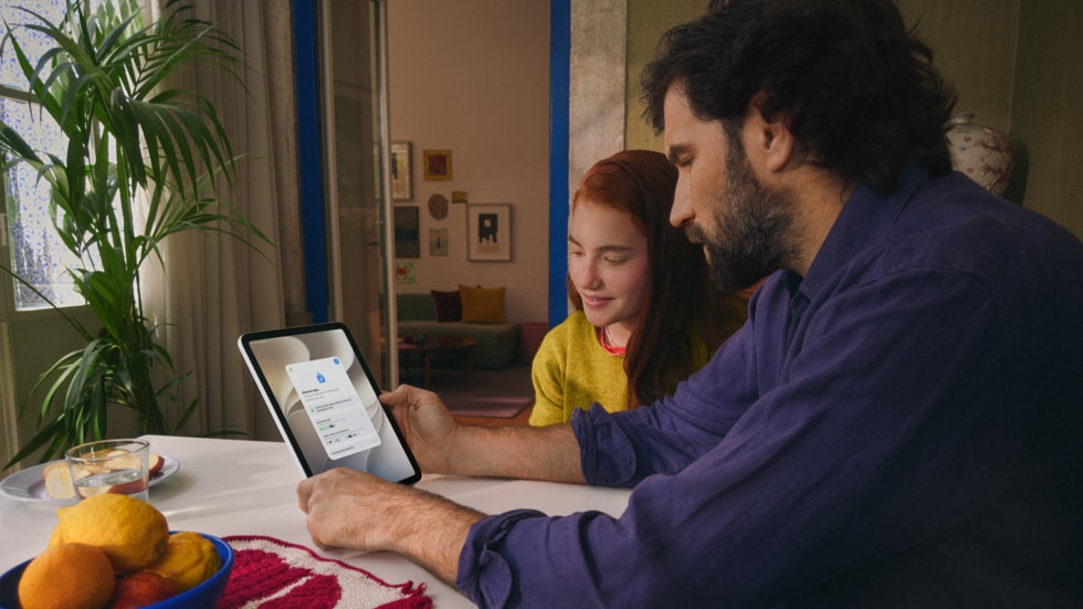 大人と子どもが木製のテーブルで一緒に座り、iPadでやり取りしている様子