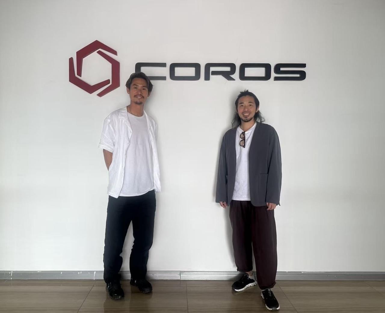 COROS中国本社のCOROSロゴ前に立つTWOLAPSの2人 製品開発現場やブランド理念視察