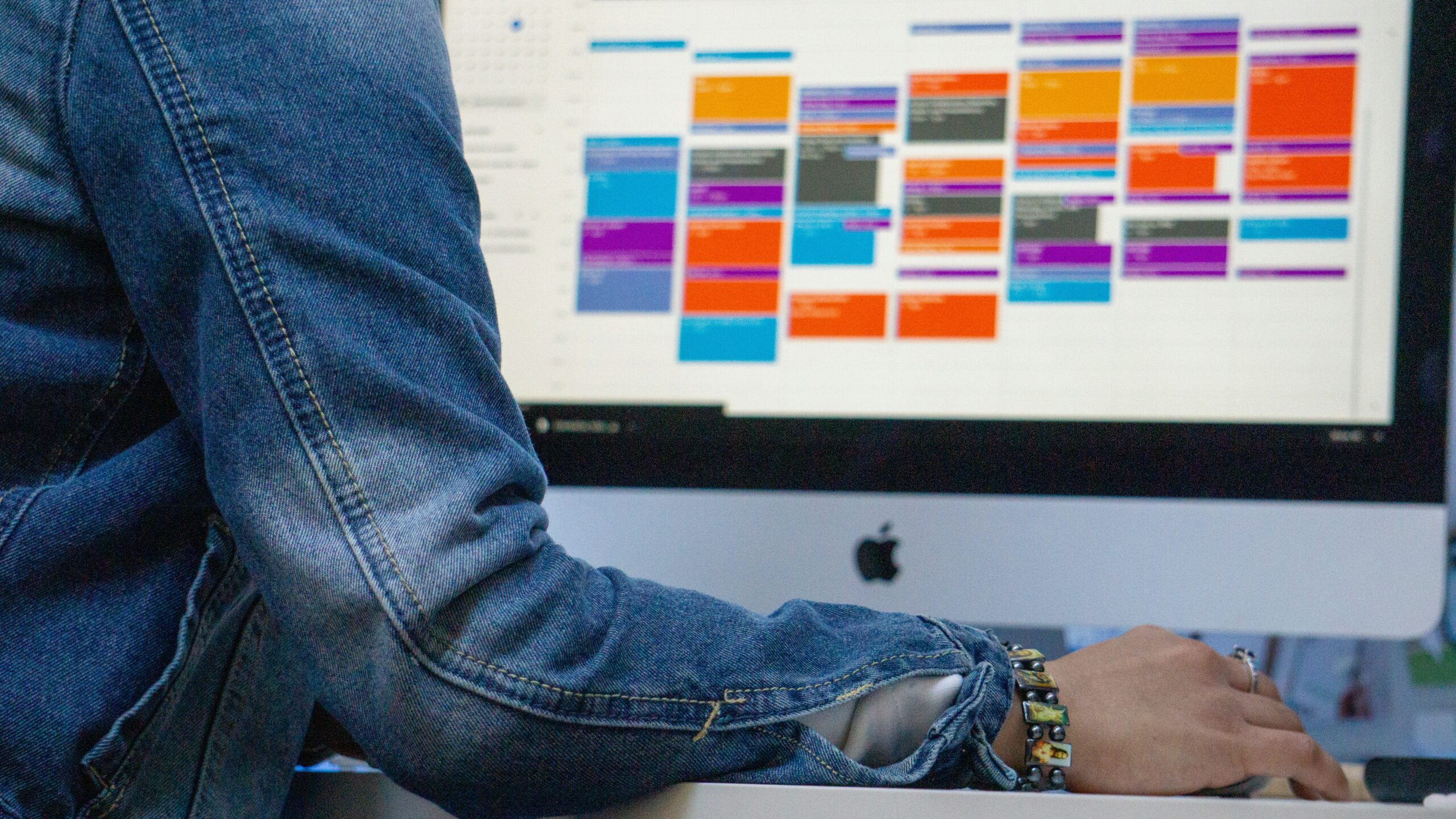 iMacに向かって作業する人。自分のMacのプライバシー設定を確認するイメージ