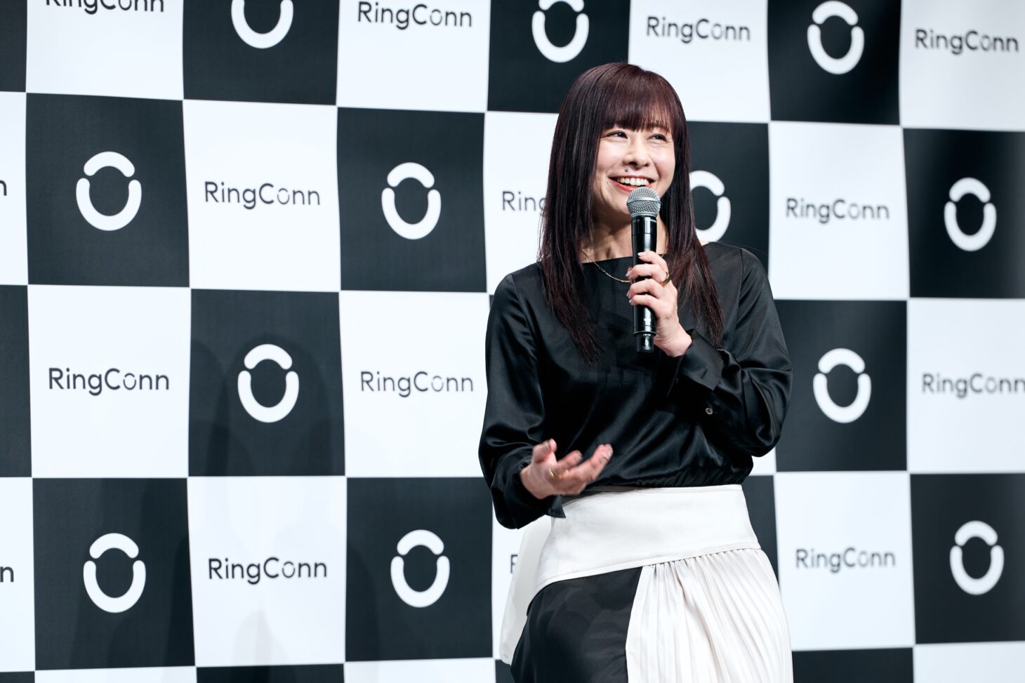 健康科学者・医学博士 本田由佳先生が笑顔でマイクを持ってトーク。RingConnロゴパネル前