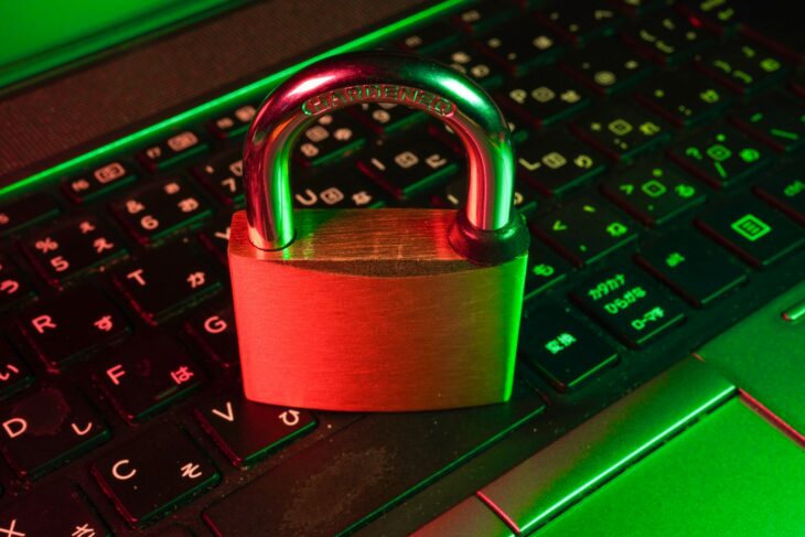 黒いキーボードの上に置かれた赤い南京錠。サイバー攻撃とセキュリティのイメージ
