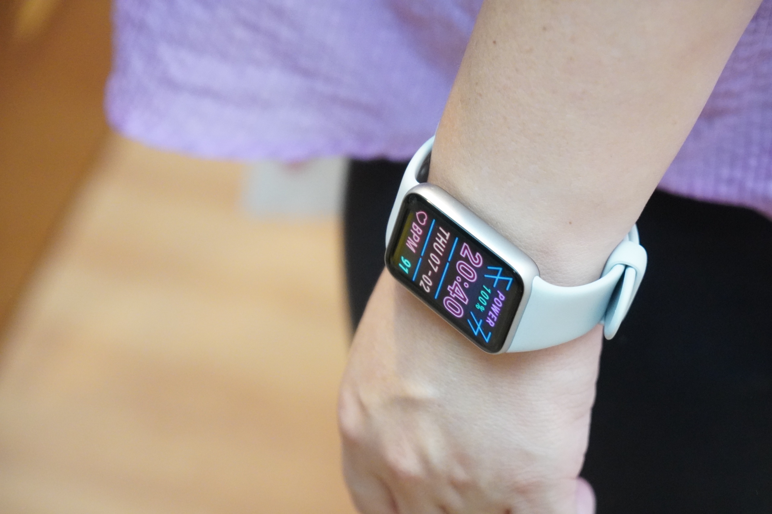 Xiaomi Smart Band 10 Pro を着けた女性の腕元。ピンクのウォッチフェイスとコーディネート