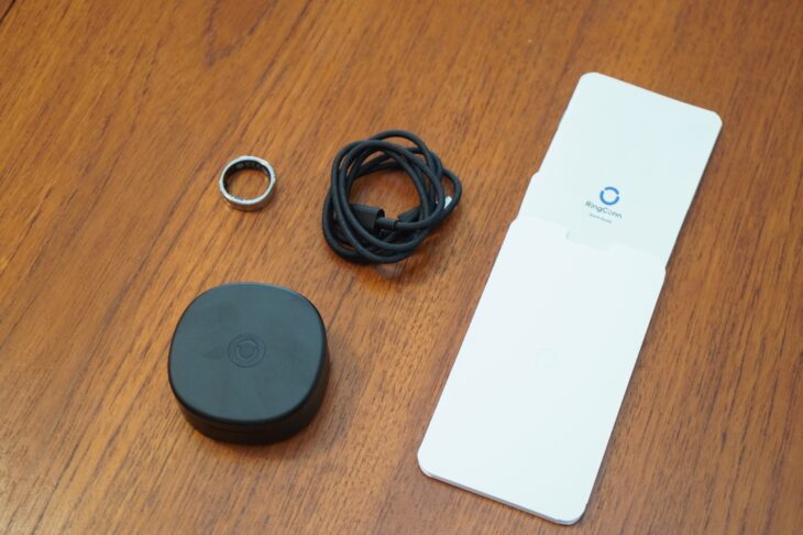 RingConn Gen 3 の同梱物一式。左からリング本体、束ねたUSB-C充電ケーブル、黒い円形の充電ケース、白いクイックスタートガイド