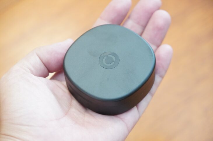 RingConn Gen 3 の充電ケースを手のひらに乗せたところ。黒い円形で、天面にRingConnのロゴが控えめに入っている
