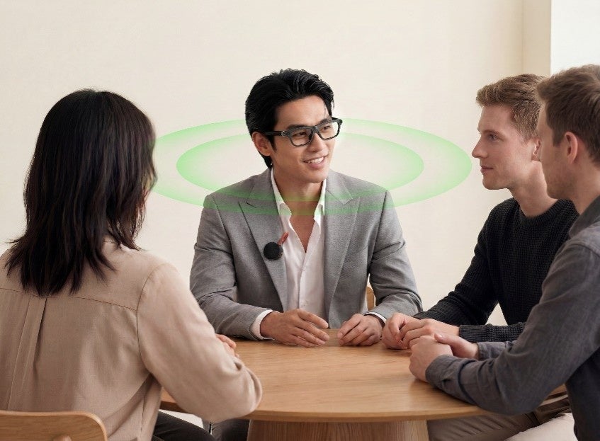 INMO GO3 を装着した男性が、胸元にINMO Speakerを付けて外国人を含む複数人と会話しているイメージ
