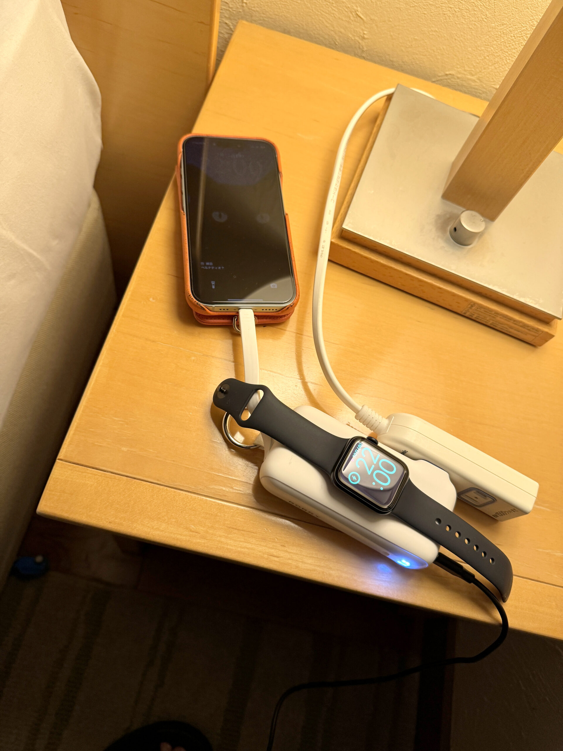 ホテルのベッドサイドでRORRY FlowからiPhoneとApple Watchを同時に充電している様子