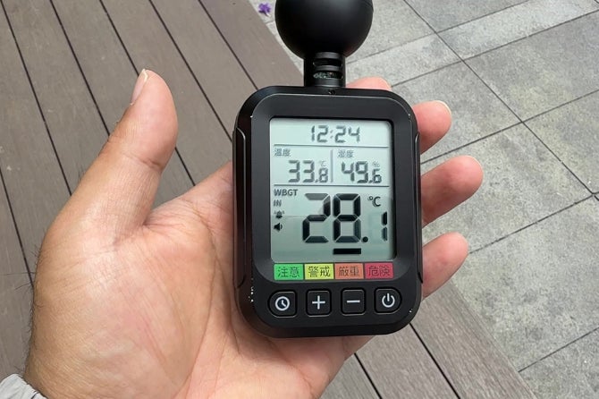 本体の画面に温度・湿度・WBGT・体感温度を表示する「スゴい暑さ指数アラート」を手に持った様子。