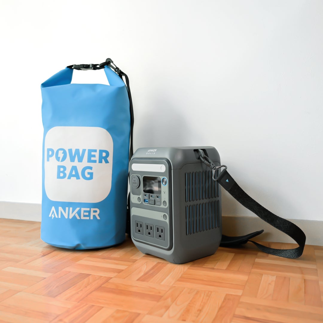 防災セット「Anker PowerBag 2026」。ブルーの防水ドライバッグと、ショルダーストラップが付いたグレーのポータブル電源Anker Solix C300が床に並んでいる