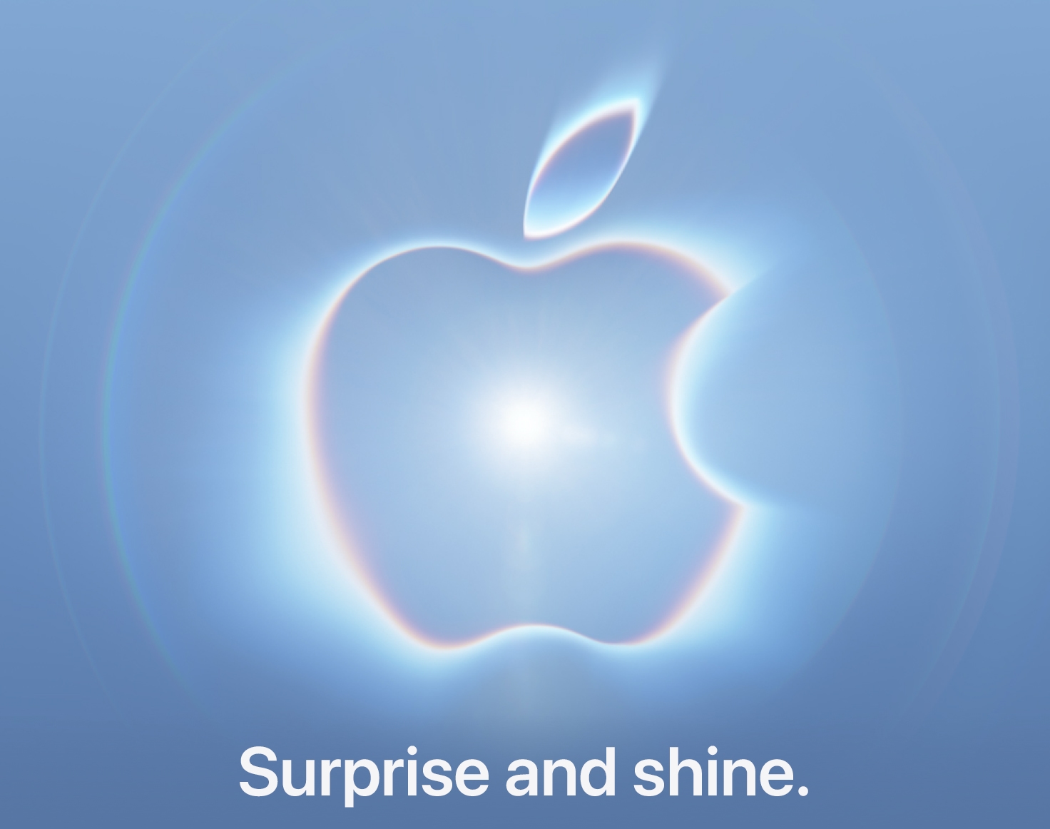 Appleのスペシャルイベント招待状の英語版。青いグラデーションの背景に光を放つAppleロゴが浮かび、下部に英語のタグライン「Surprise and shine.」が置かれている