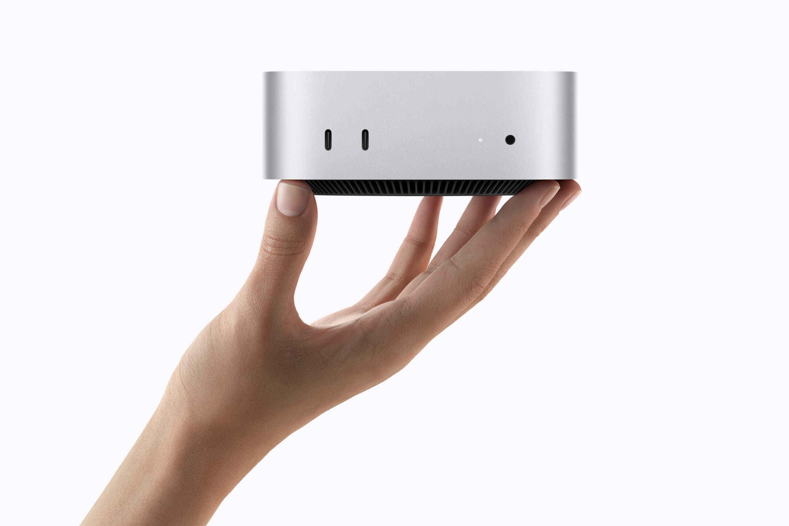 手のひらに載せた新しいMac mini。アルミニウムの小さな筐体で、前面にUSB-Cポート2つとヘッドフォンジャックが見える