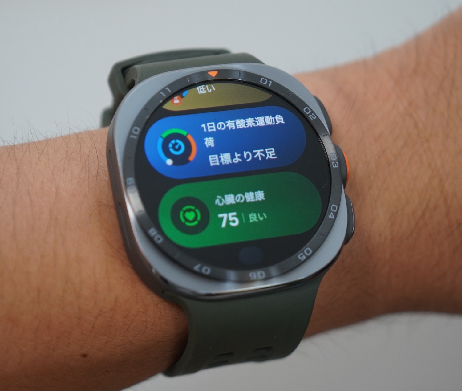 Galaxy Watch Ultra2のホーム画面。1日の有酸素運動負荷「目標より不足」の下に、心臓の健康スコア75「良い」が緑のカードで表示されている。