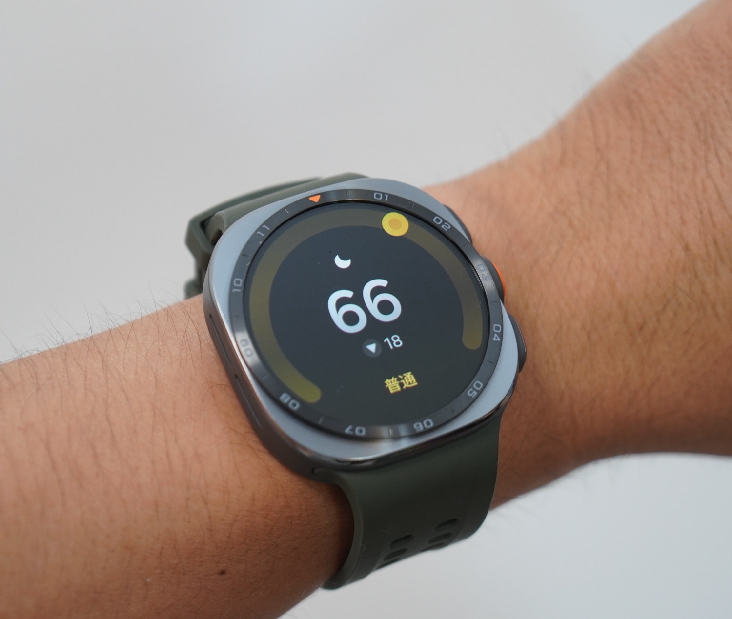 Galaxy Watch Ultra2を腕に着けた状態で、睡眠スコア66「普通」と前日比マイナス18が表示されている画面。