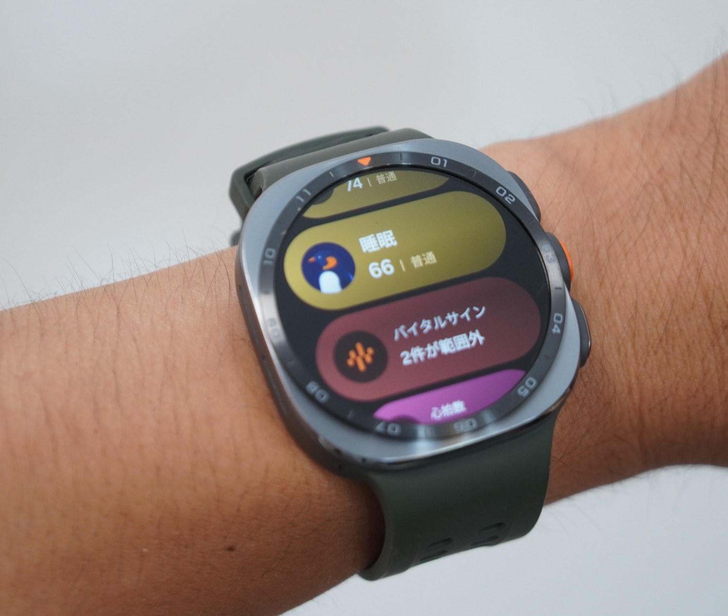 Galaxy Watch Ultra2のホーム画面。睡眠スコア66とペンギンのスリープアニマル、その下にバイタルサイン「2件が範囲外」、さらに心拍数のカードが並んでいる。