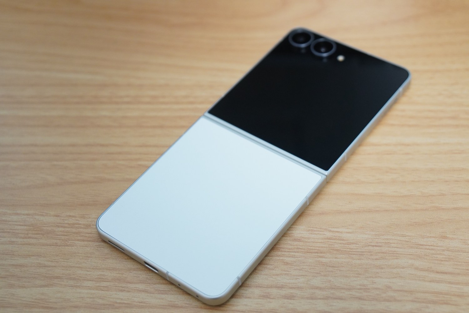 Galaxy Z Flip8の背面全体。上半分の黒いカバー画面と下半分のクリーム色のボディという2トーン構成で、カメラは縦に2眼。