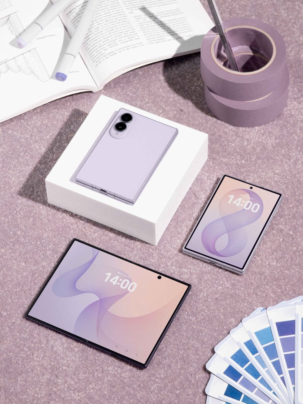 ラベンダーカラーのSamsung Galaxy Z Fold8を開いた状態とパッケージ、カラーサンプルを並べた写真