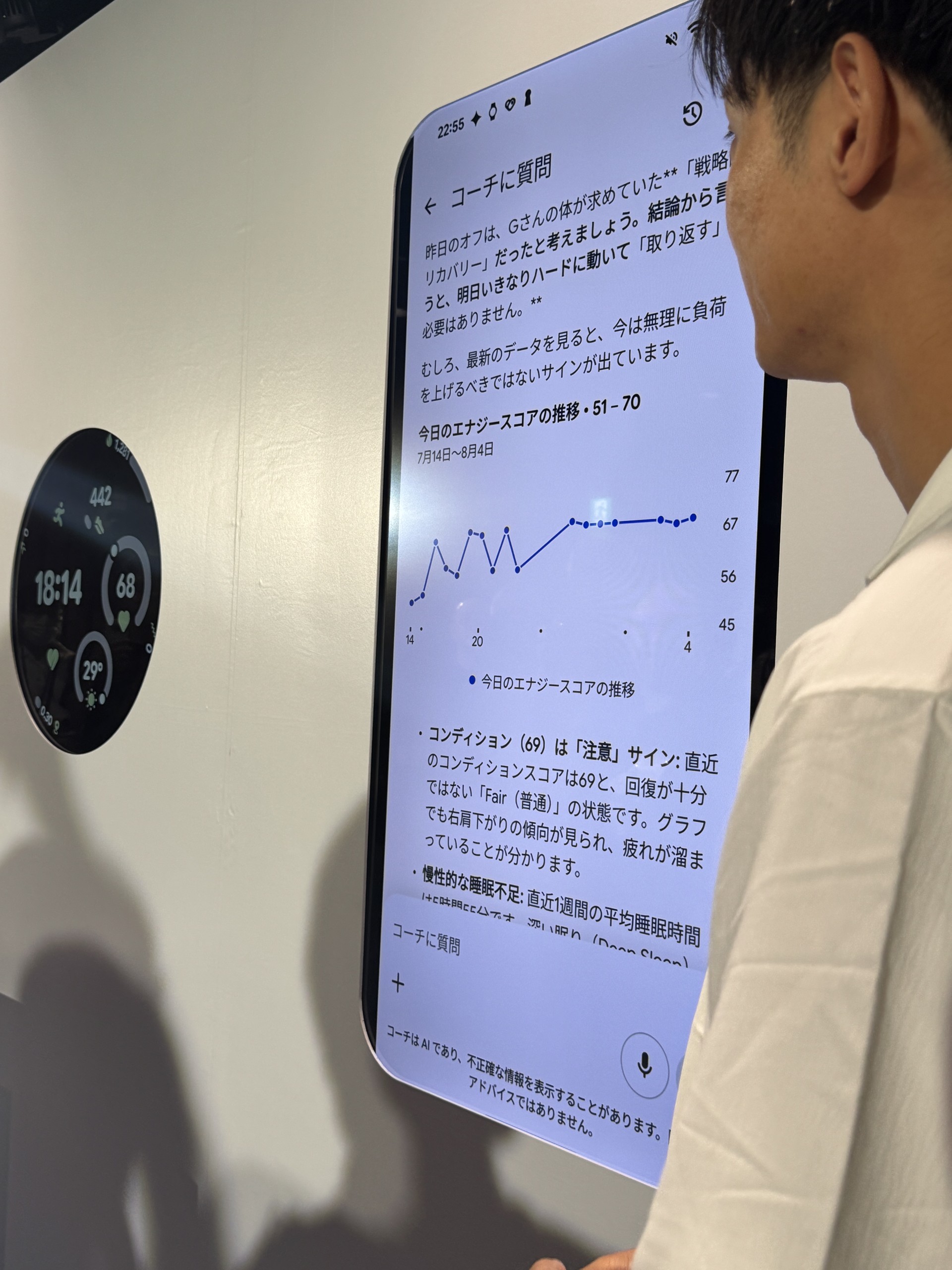 デモ会場の大型ディスプレイに「コーチに質問」の画面が映り、エナジースコアの推移グラフと助言が表示されている