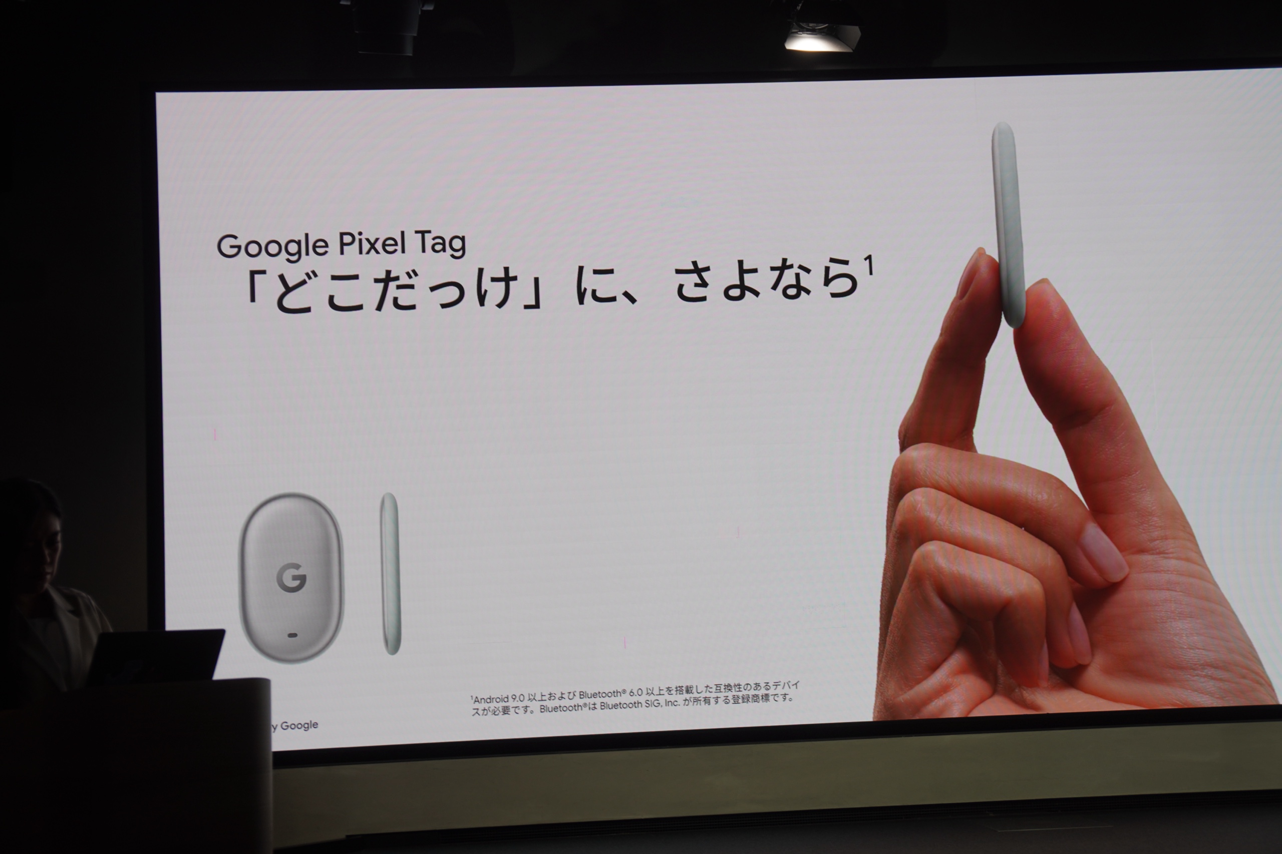 指先でつままれた小さな楕円形の Google Pixel Tag 本体