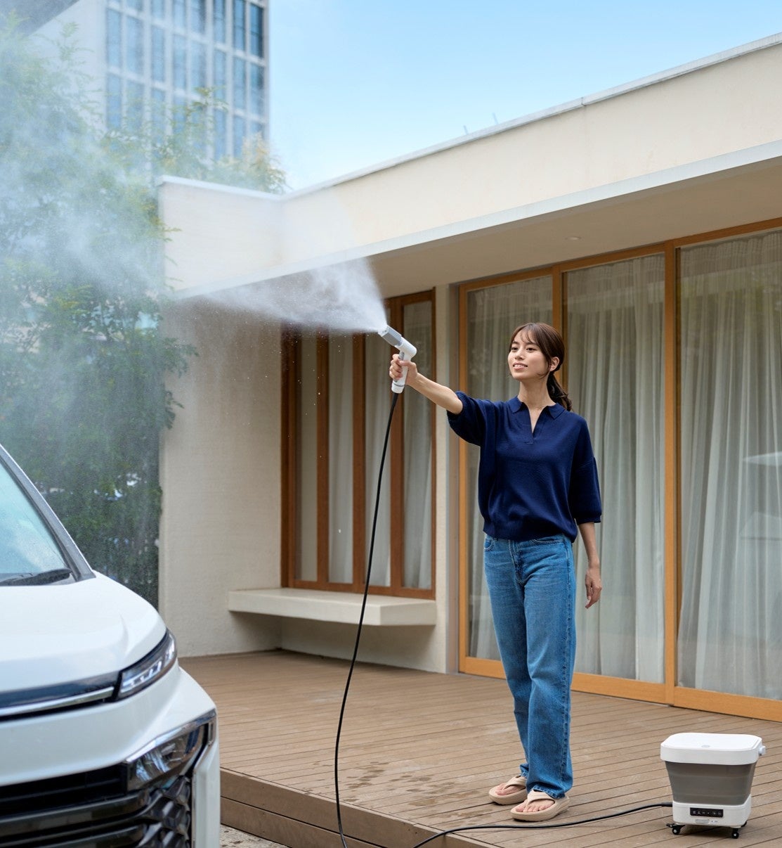 MIRABLE AQUABLAST MINIをベランダで使い、屋外を洗浄している様子。手前には車が停まっている