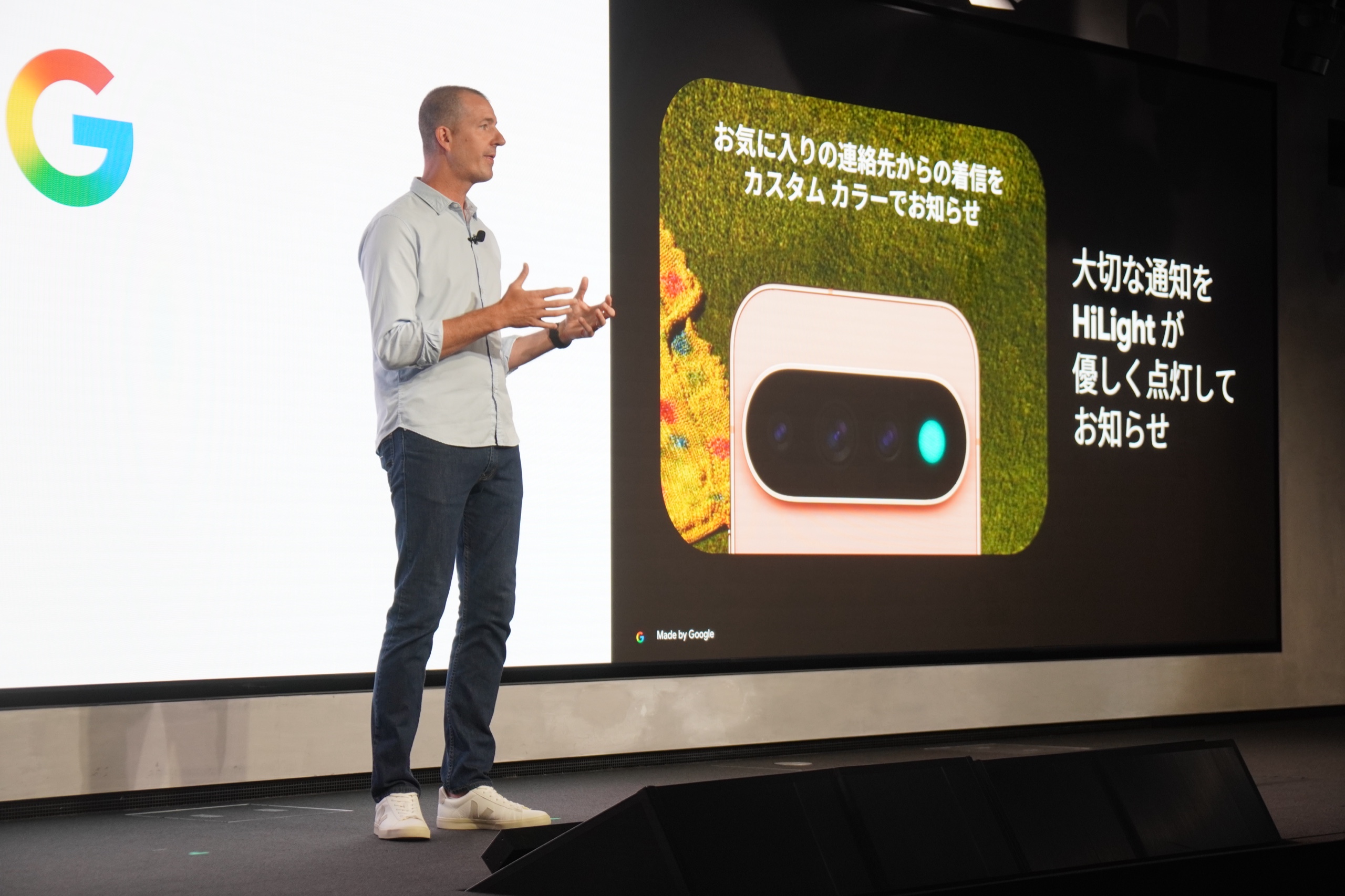 説明会のステージに映された HiLight のスライド。背面カメラバーの一部が水色に点灯した Pixel 11 が大写しになっている