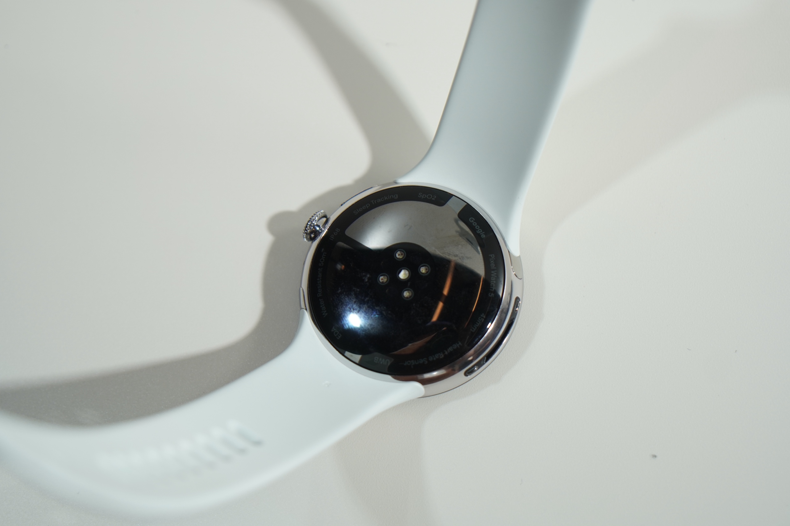 白いバンドの Pixel Watch 5 の裏面。円形のセンサー部が中央にある
