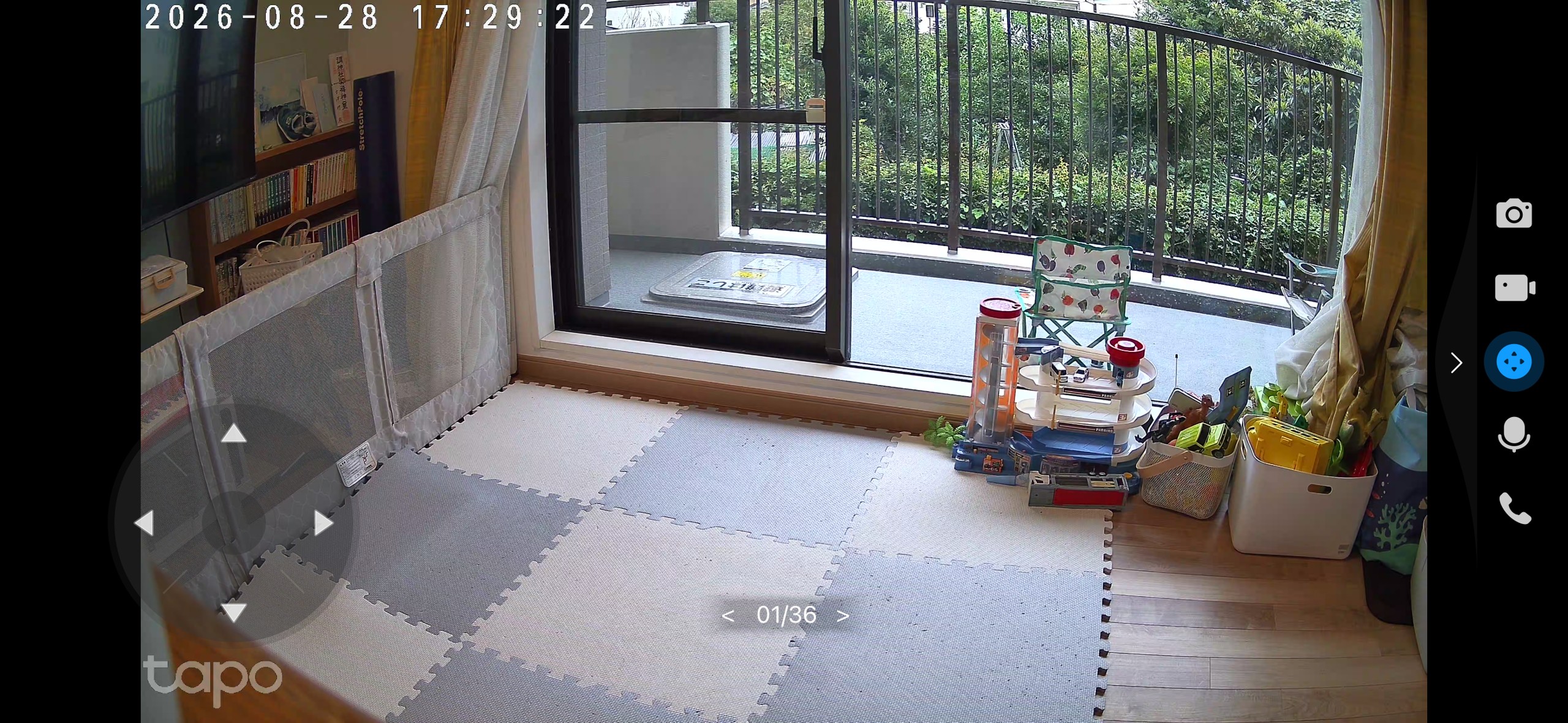 Tapo C260のライブ映像で映したリビング。掃き出し窓の向こうのバルコニーと植栽の緑、床のジョイントマット、部屋の隅にまとめられたおもちゃまでひと画面に収まっている