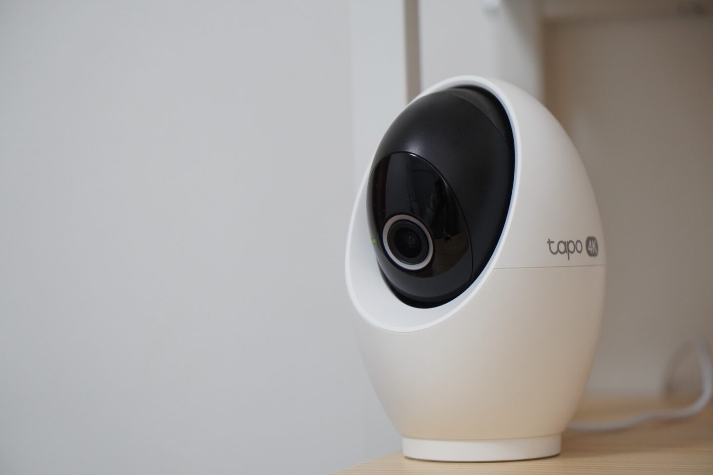Tapo C260を寝室の棚の上に単体で置いたカット。白い壁を背景に、卵型の白いボディと黒いレンズ部、tapo 4Kのロゴ、緑の動作ランプが見える