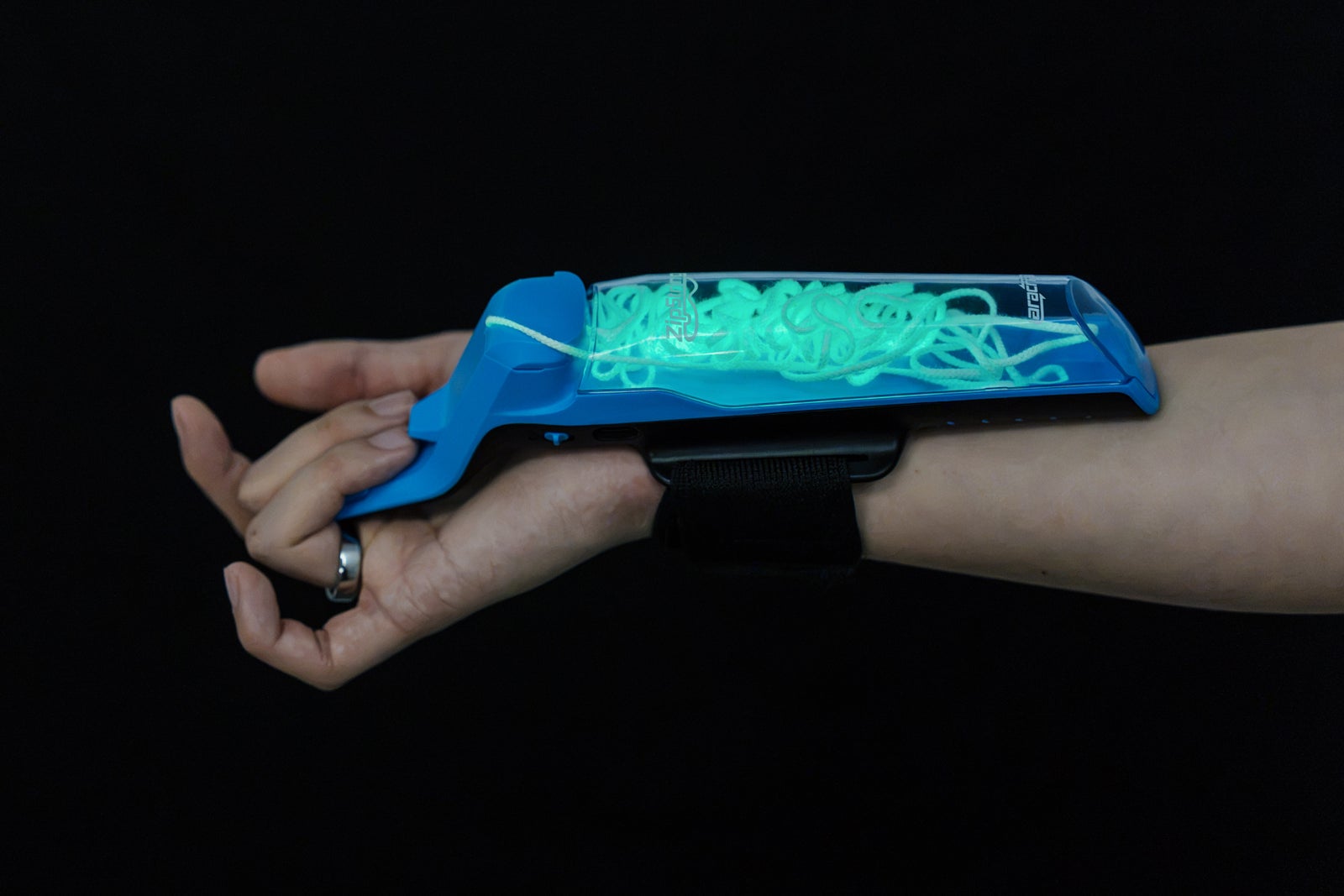 暗闇の中でグローストリングが緑色に発光しているZipString Aracnaを腕に装着した様子