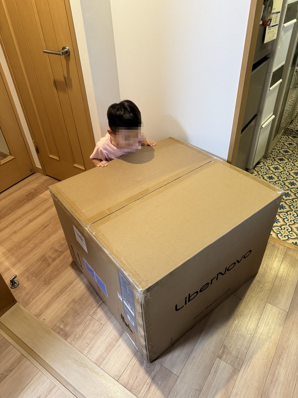 玄関に届いたLiberNovo Omni Proの梱包箱。子どもが横に立つと、箱の大きさがよく分かる