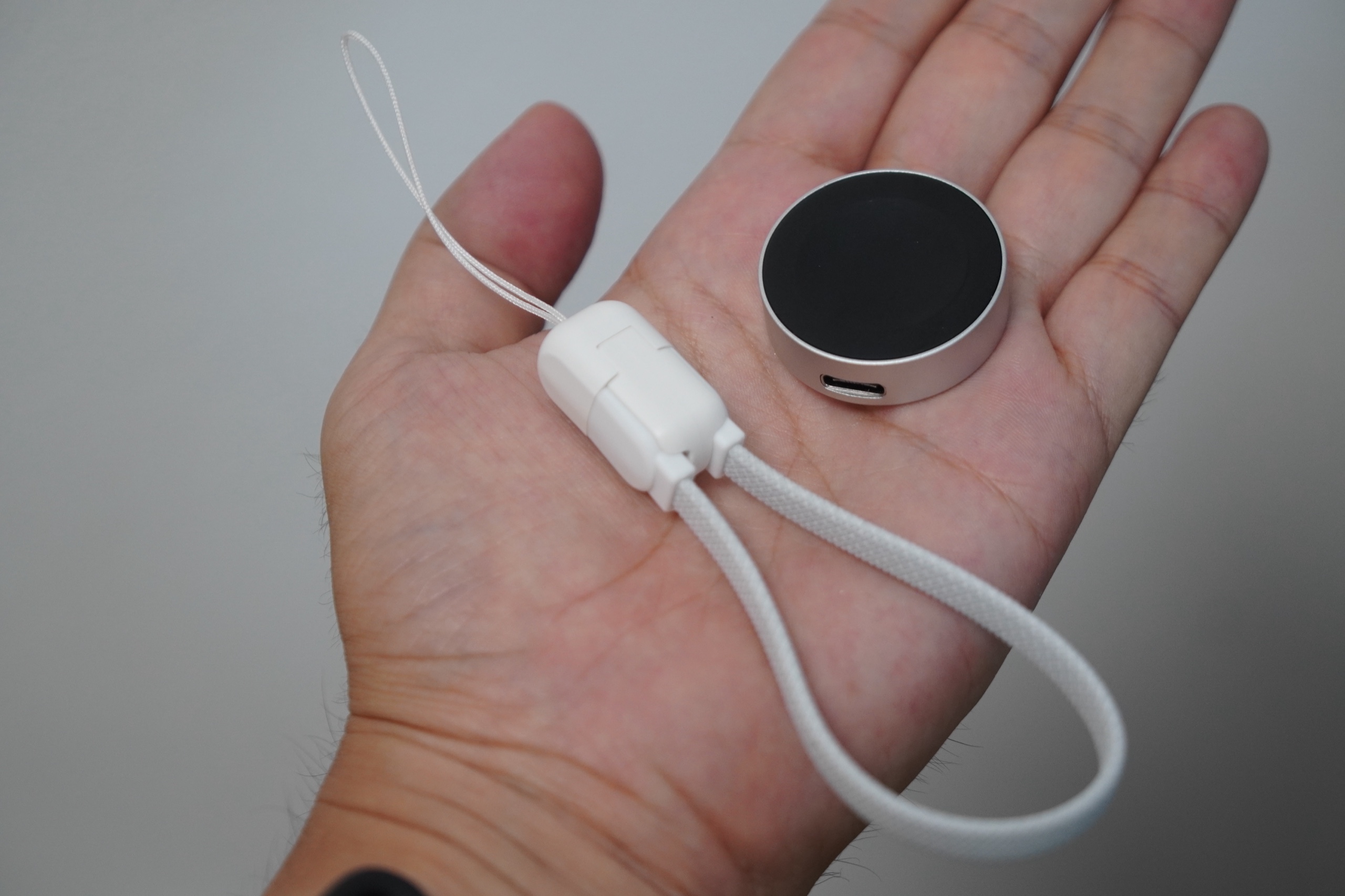 手のひらに載せたsymoode充電器本体とストラップ形態のケーブル