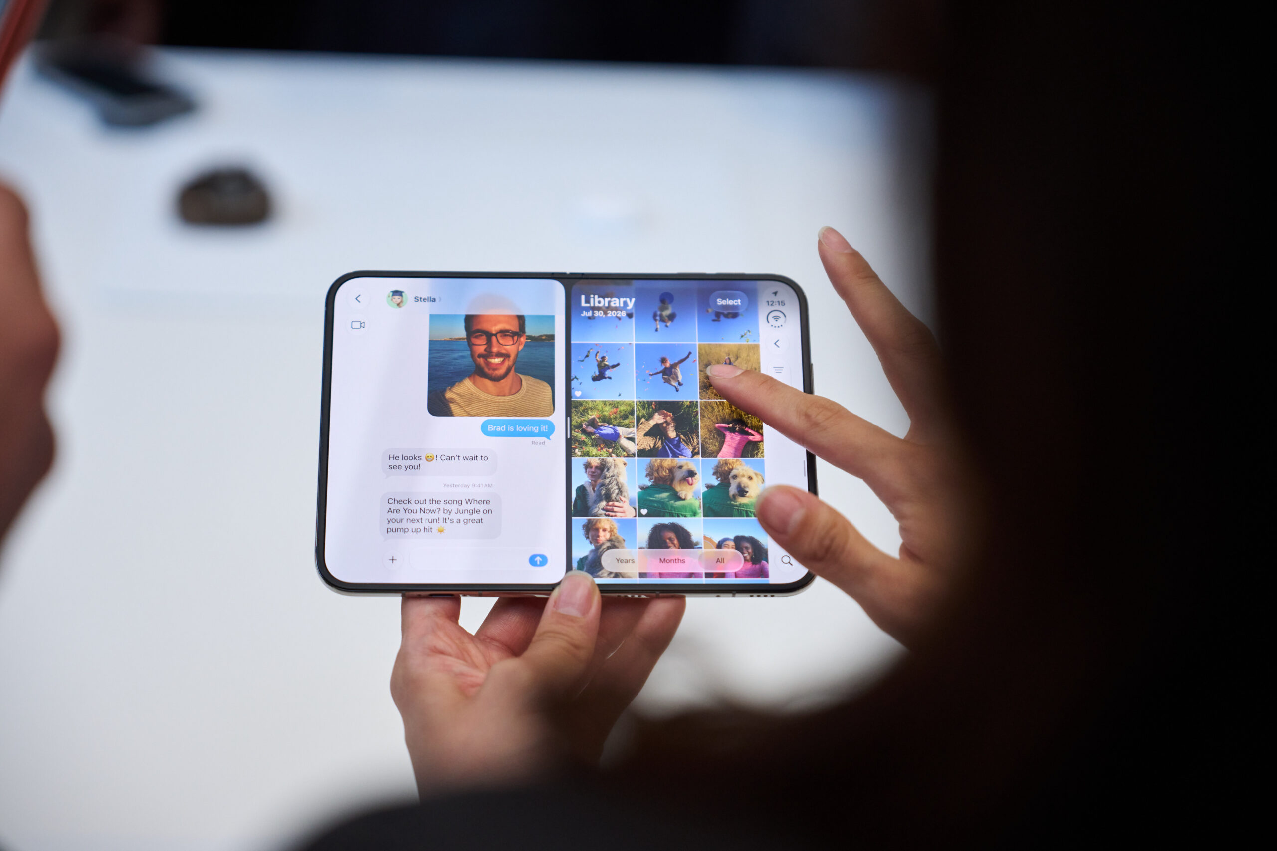 Appleのスペシャルイベント会場で、開いた状態のiPhone Duoの画面を操作する手元