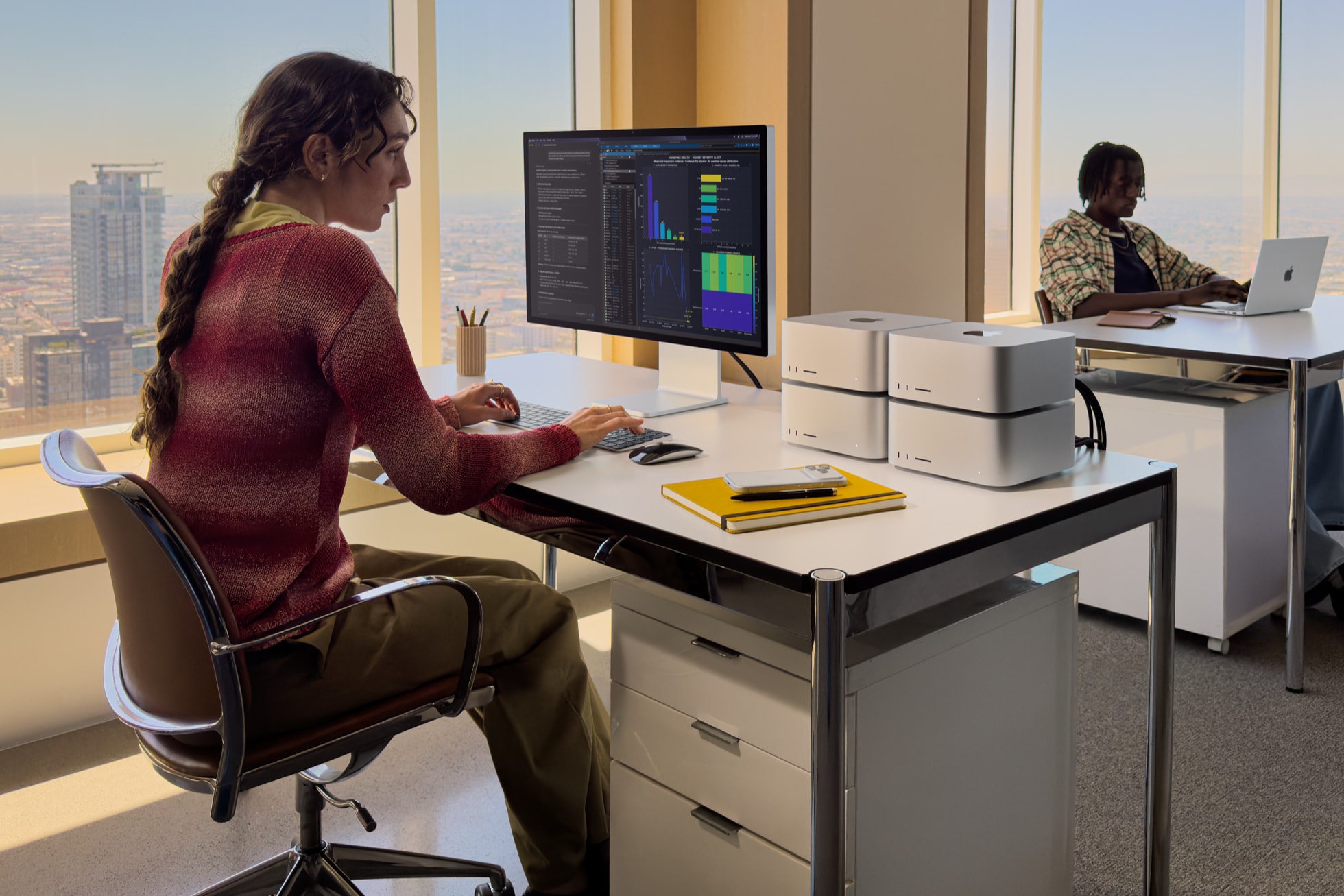 オフィスの机にMac Studioが4台積み上げられ、外部ディスプレイでデータ分析の画面を見ながら作業している様子