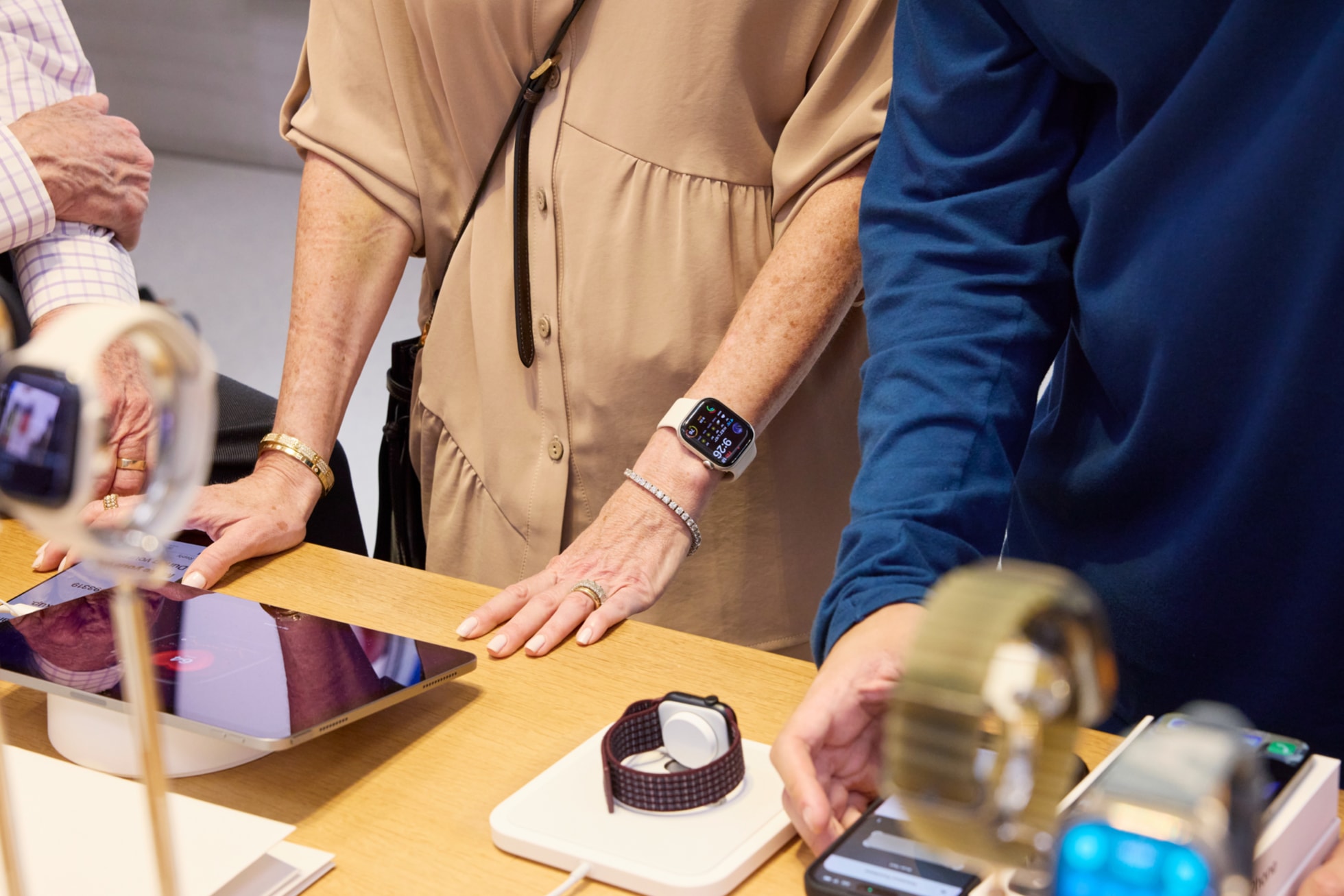 Apple Fifth AvenueのApple Watchのディスプレイテーブルで、iPadとiPhoneと一緒にApple Watchモデルを試している来店客。
