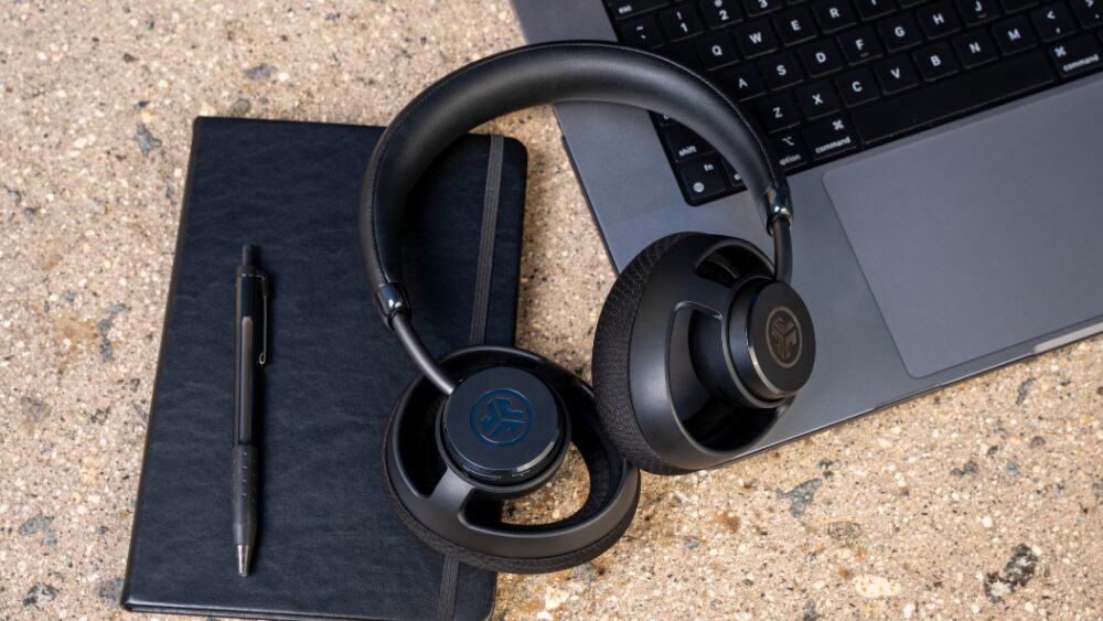 ノートPCとノートの上に置かれたJLabのオープンイヤー型ワイヤレスヘッドホン JBuds Open Wireless