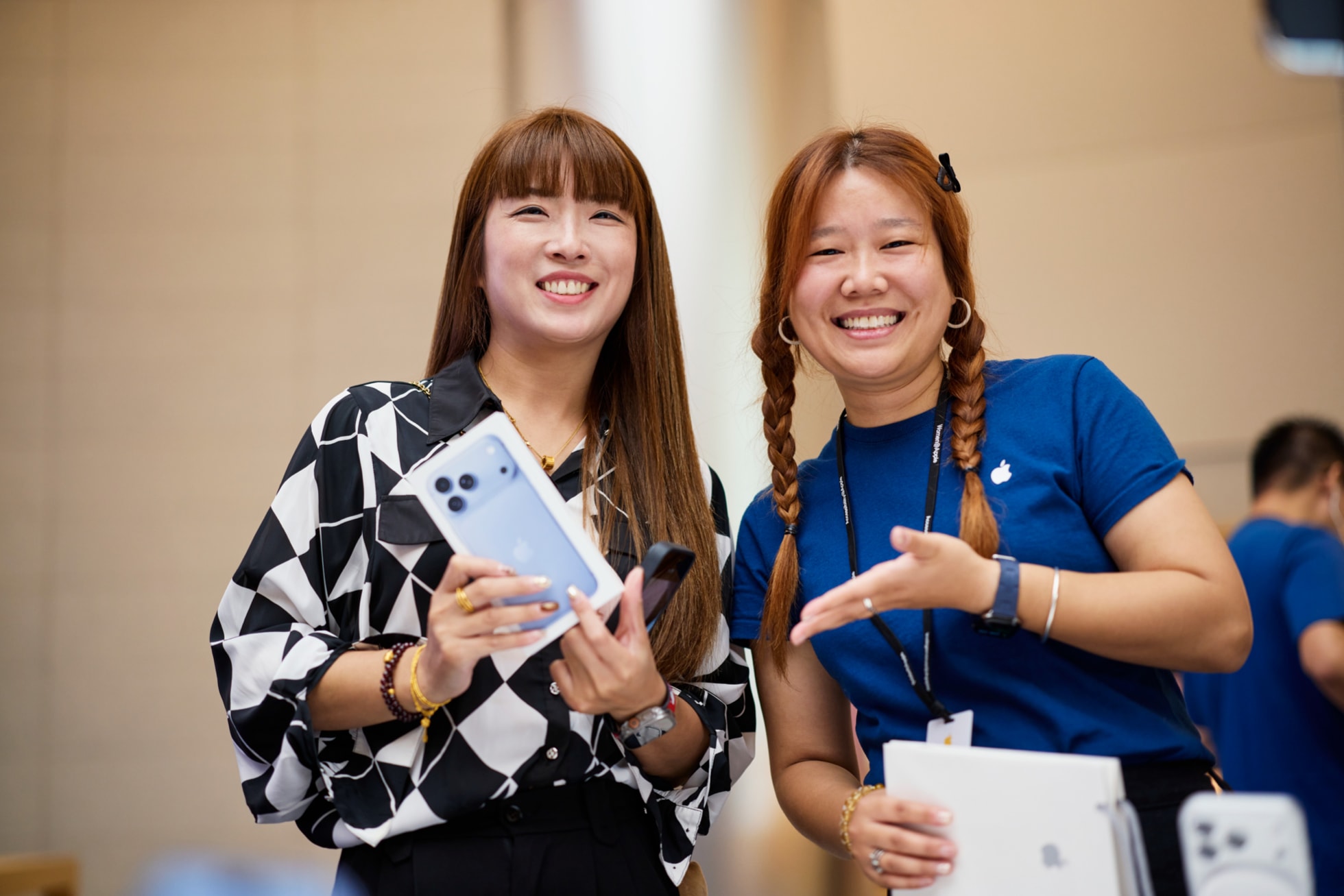 笑顔のApple Jing’anのチームメンバーの横で、購入したiPhone 18 Proを見せている来店客。