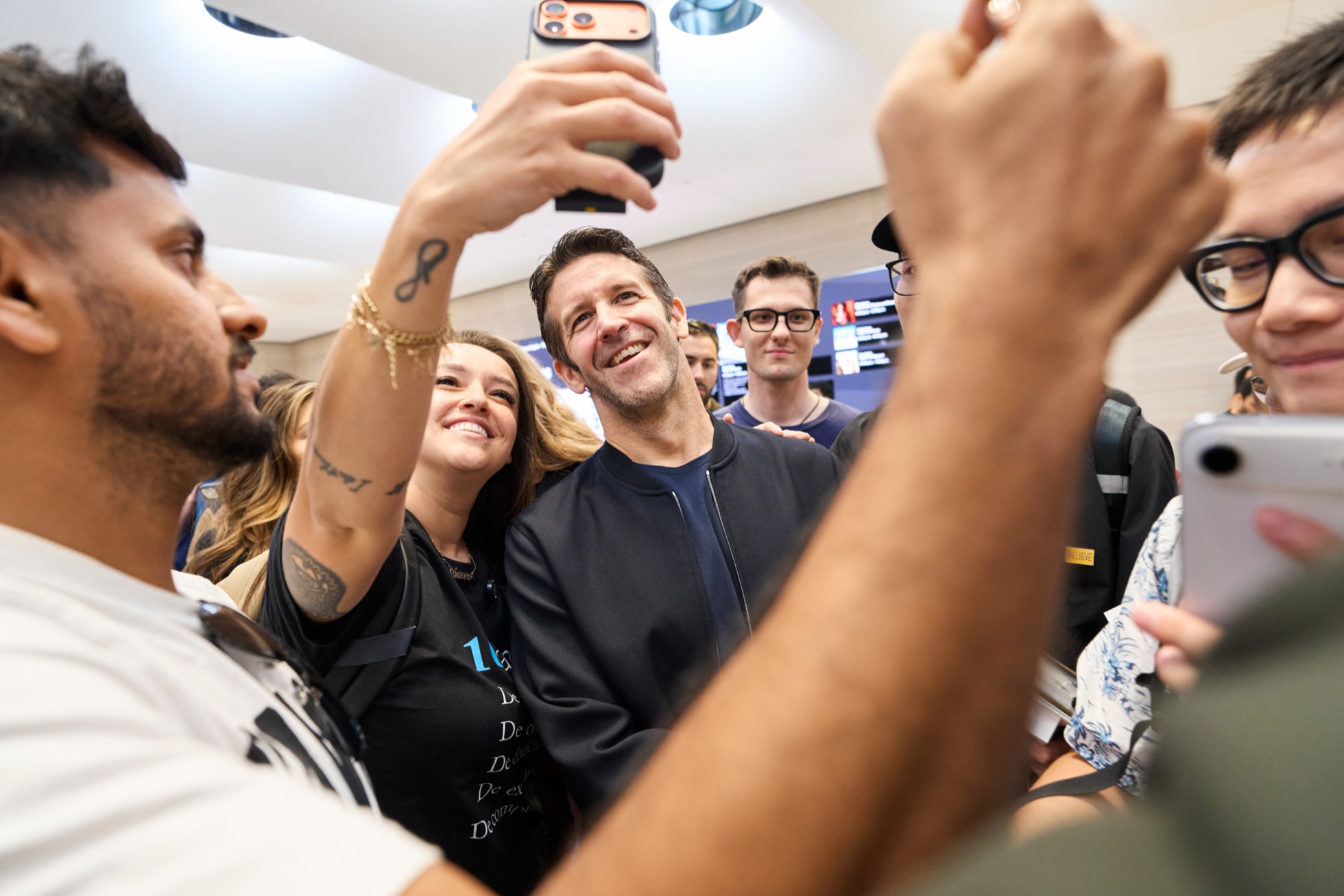 Apple Fifth Avenueで、来店客と一緒に写真撮影をしている笑顔のジョン・ターナス。