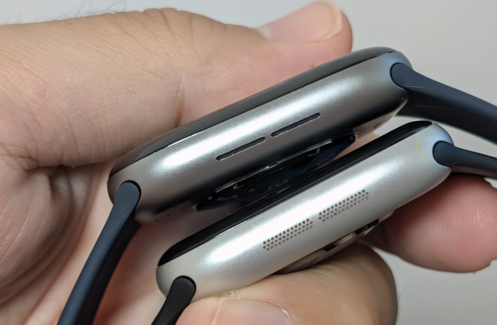 Apple Watch Series 12(上)とSeries 10(下)のスピーカー側の側面を並べた比較。Series 12は細長いスリットが2本、Series 10は小さな穴が面で並んでいる