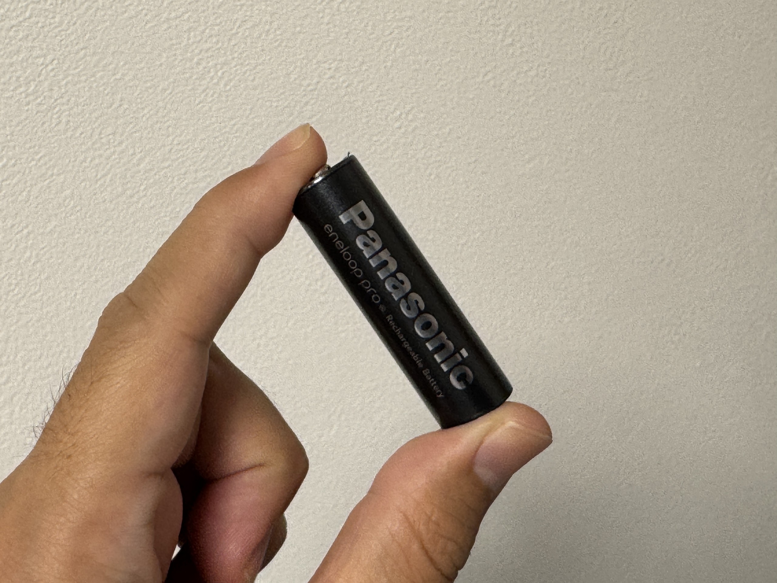 黒いエネループ プロ 単3形を親指と人差し指でつまんで斜めに持ったところ。Panasonicとeneloop proのロゴが見える