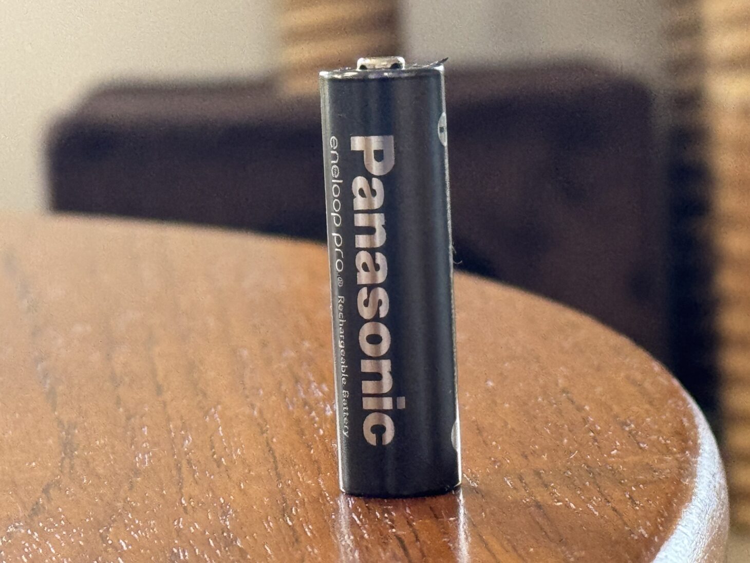 木のテーブルの上に立てた黒いエネループ。Panasonic eneloop pro Rechargeable Batteryの文字が縦に入っている