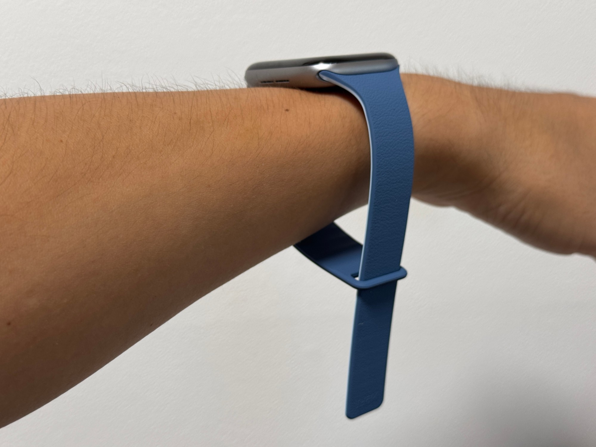 腕に着けたApple Watchのバンドを横から見たところ。一方のバンドをもう一方の先端の穴に通し、まだ留めずに先を垂らしている