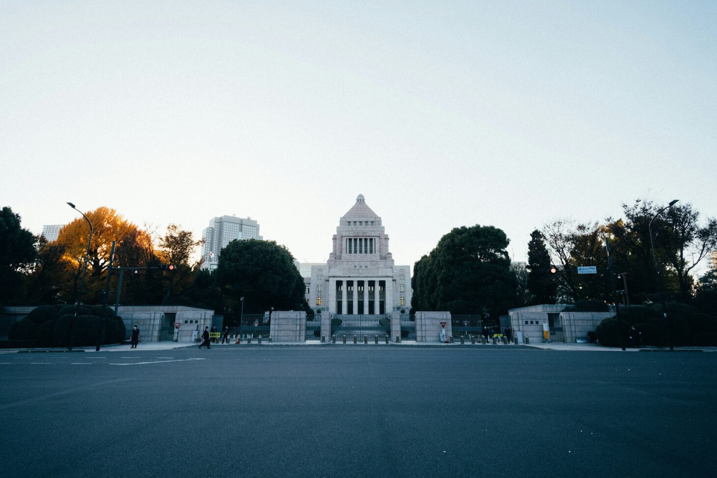 夕方の空の下、正面から見た国会議事堂。手前には広い道路が伸びている
