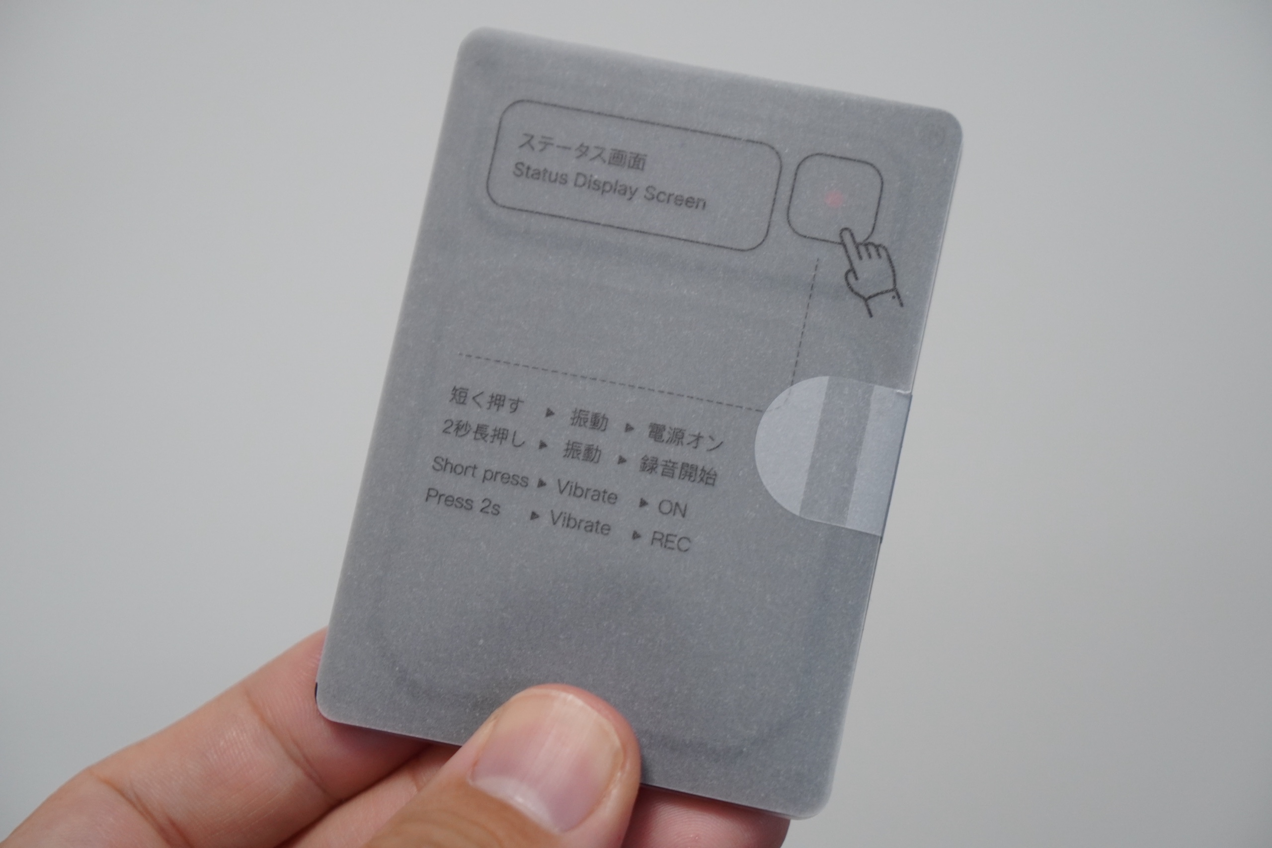 本体に貼られた保護シート。ステータス画面とボタンの位置、短く押すと電源オン、2秒長押しで録音開始という操作が印刷されている